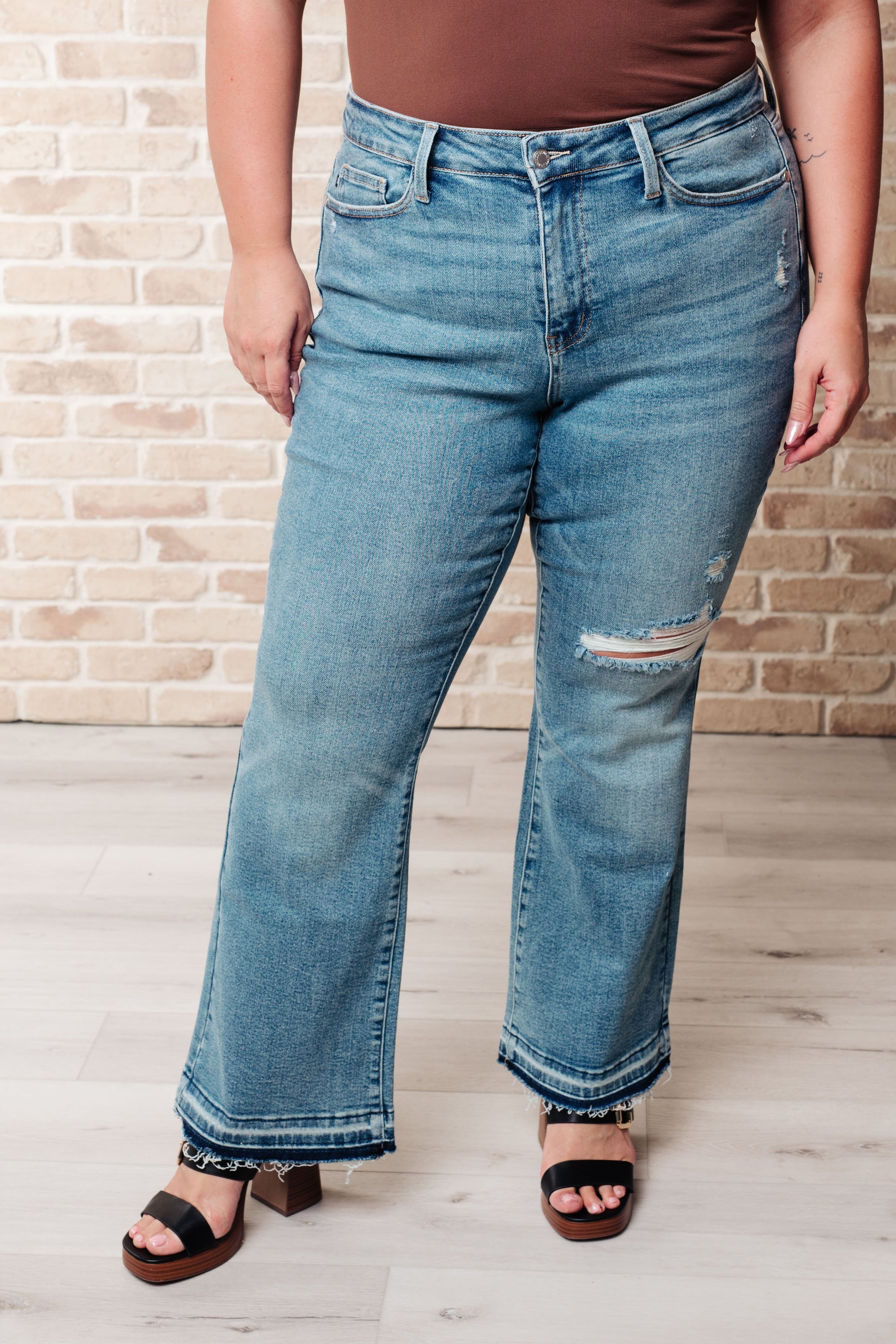 Person wearing blue jeans with a brick wall background