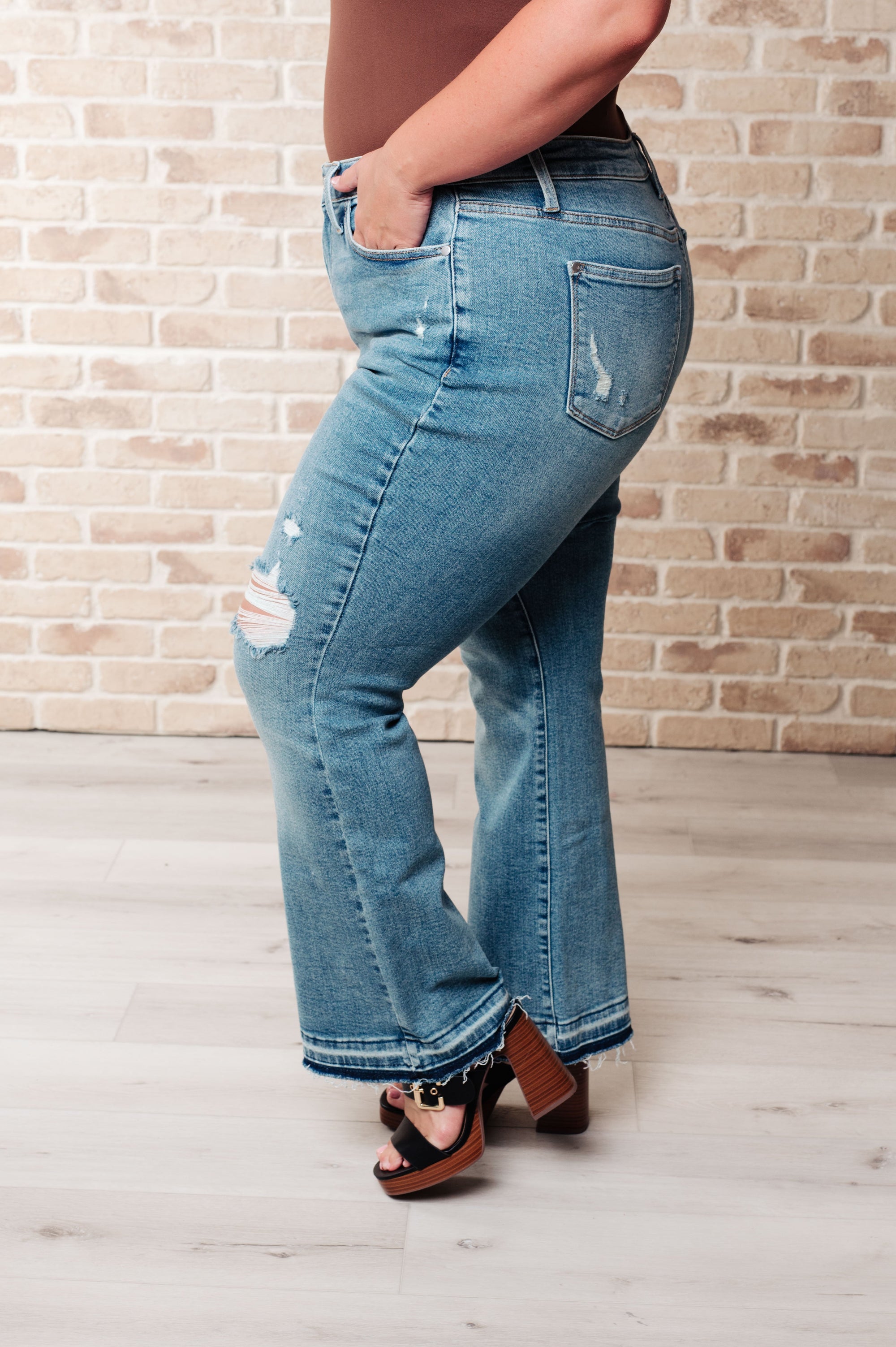 Person wearing blue jeans with a brick wall background