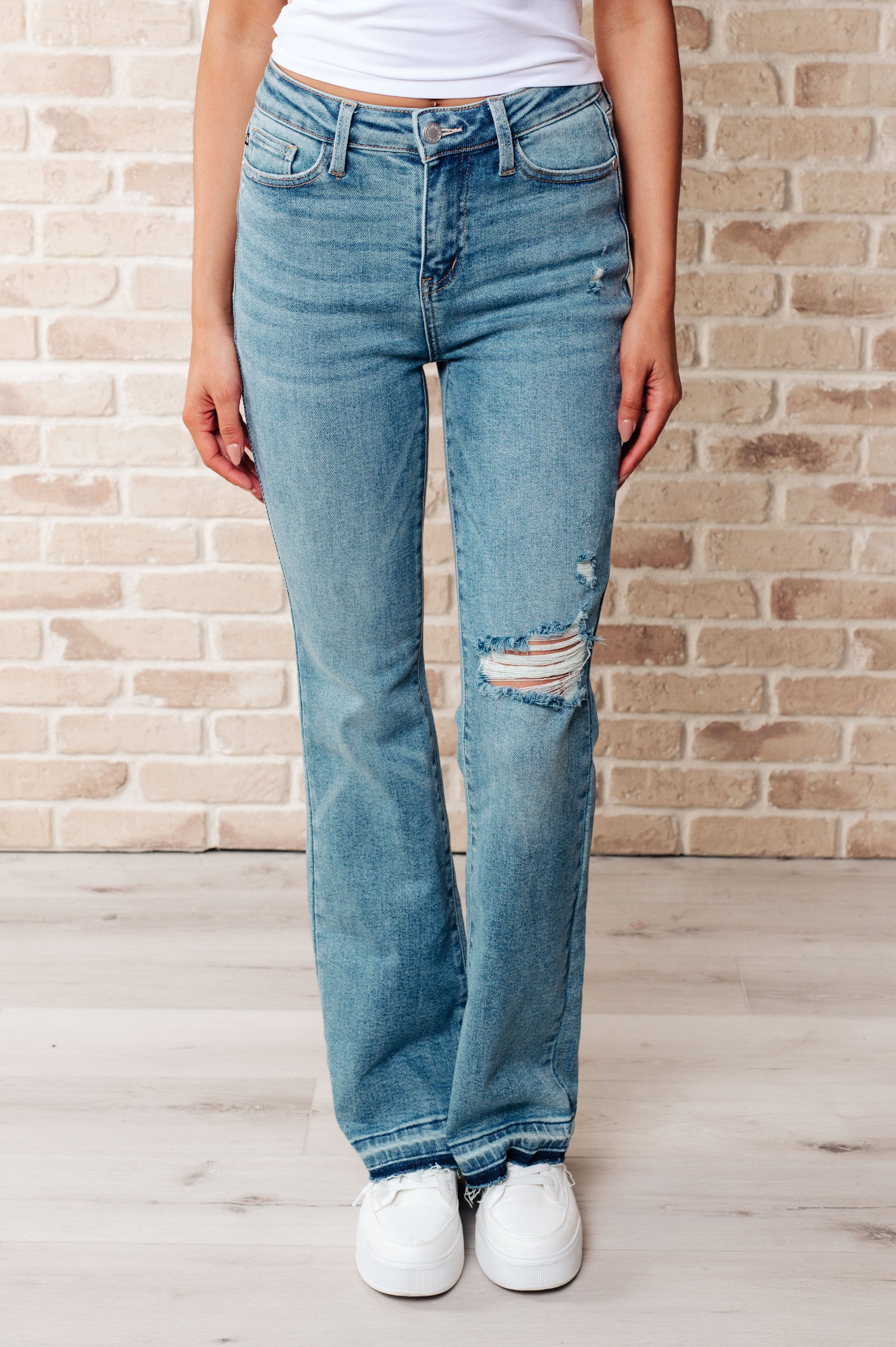 Person wearing blue jeans with a brick wall background