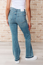 Person wearing blue jeans and a white shirt against a brick wall.