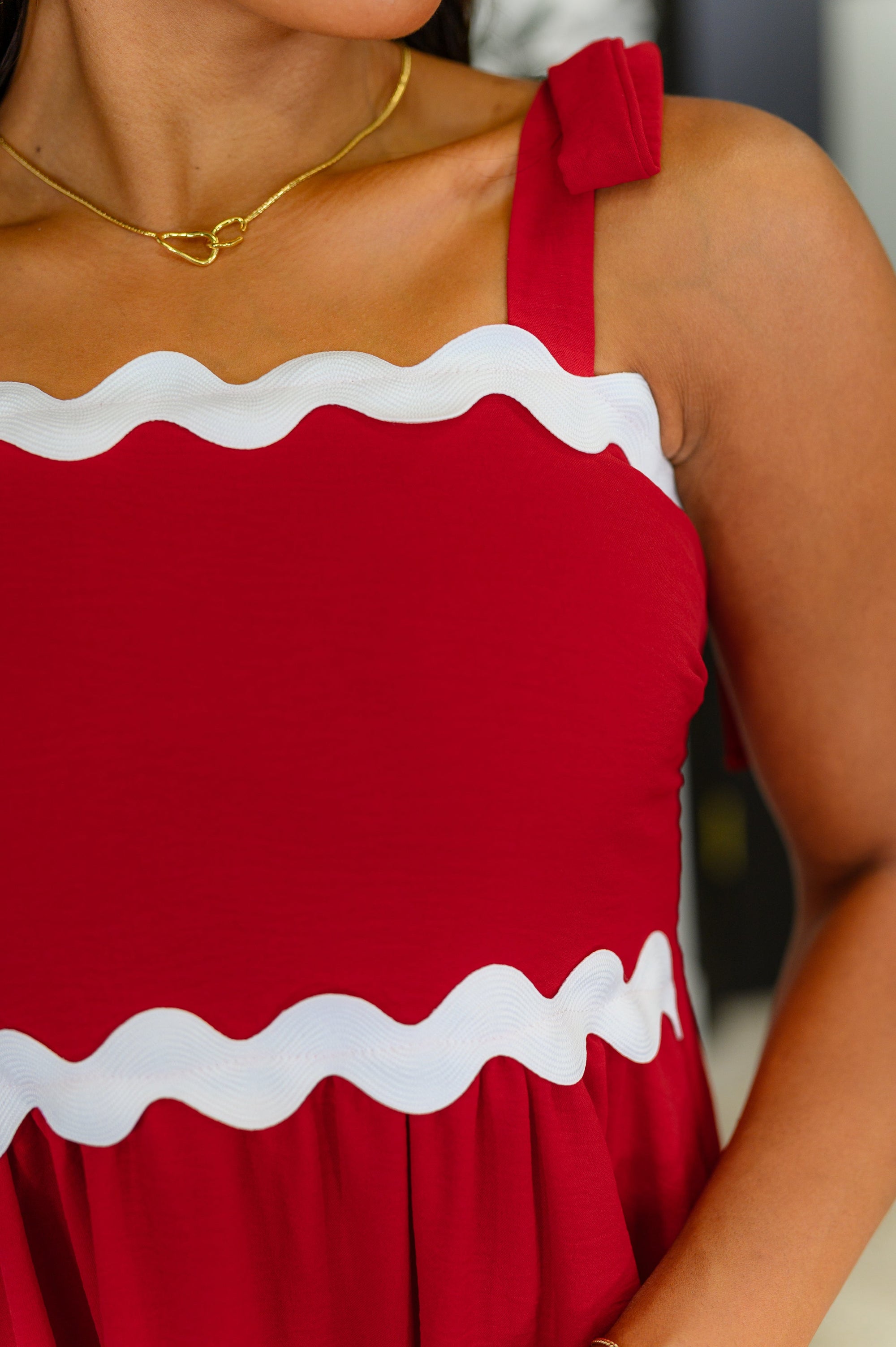 Red dress with white trim worn by a person, blurred background