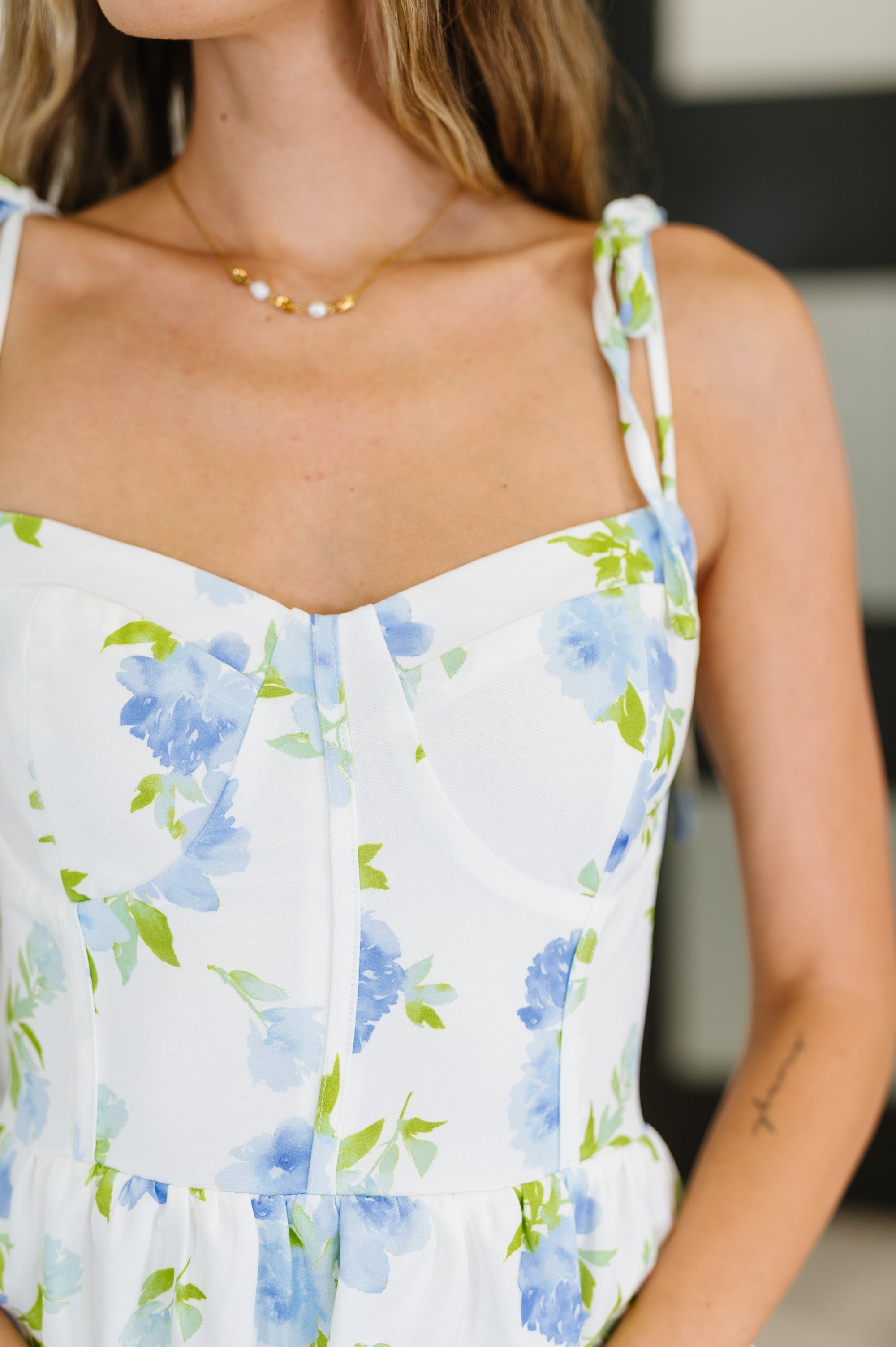 Close-up of a person wearing a floral dress with blue flowers on a white background.