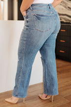 Person wearing light blue jeans standing indoors with a neutral background