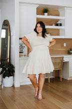 Woman in a white dress standing in a modern kitchen.