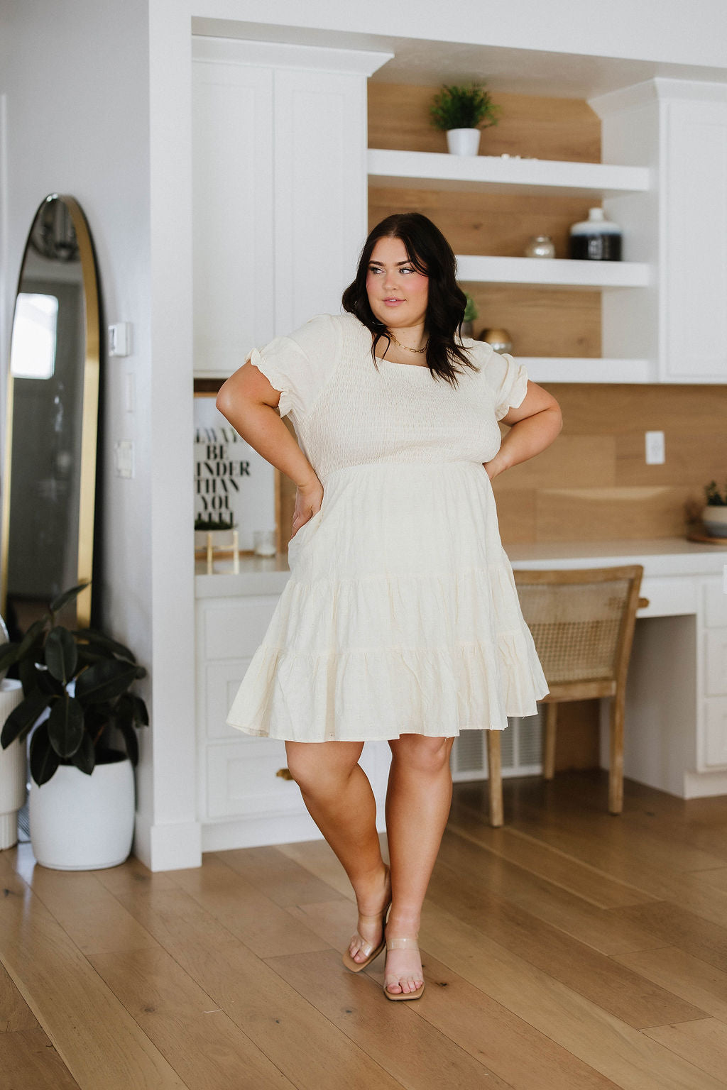 Woman in a white dress standing in a modern kitchen.