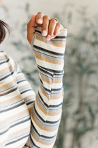 Person wearing a striped long-sleeve shirt with a blurred natural background