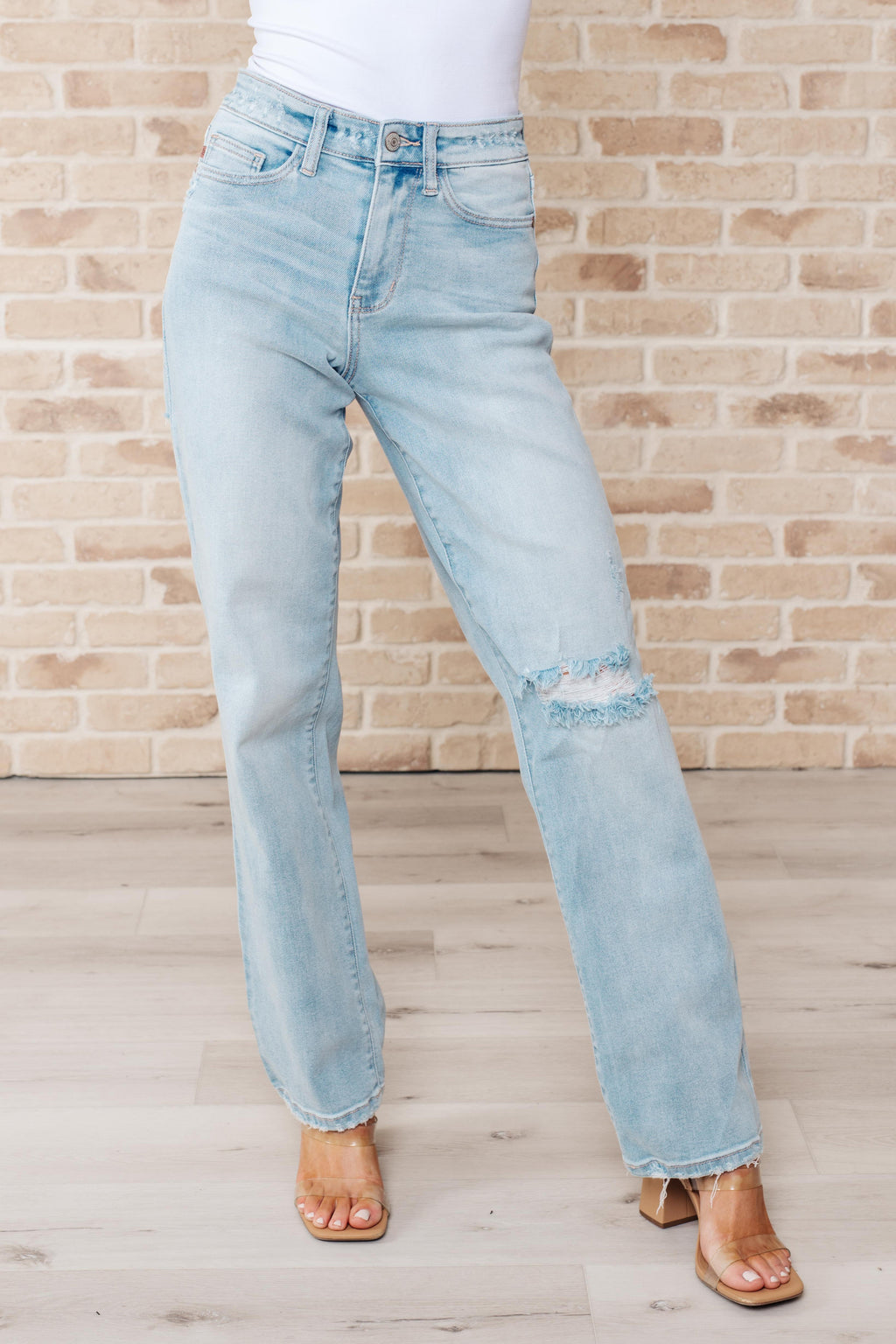 Light blue jeans worn by a person against a brick wall.