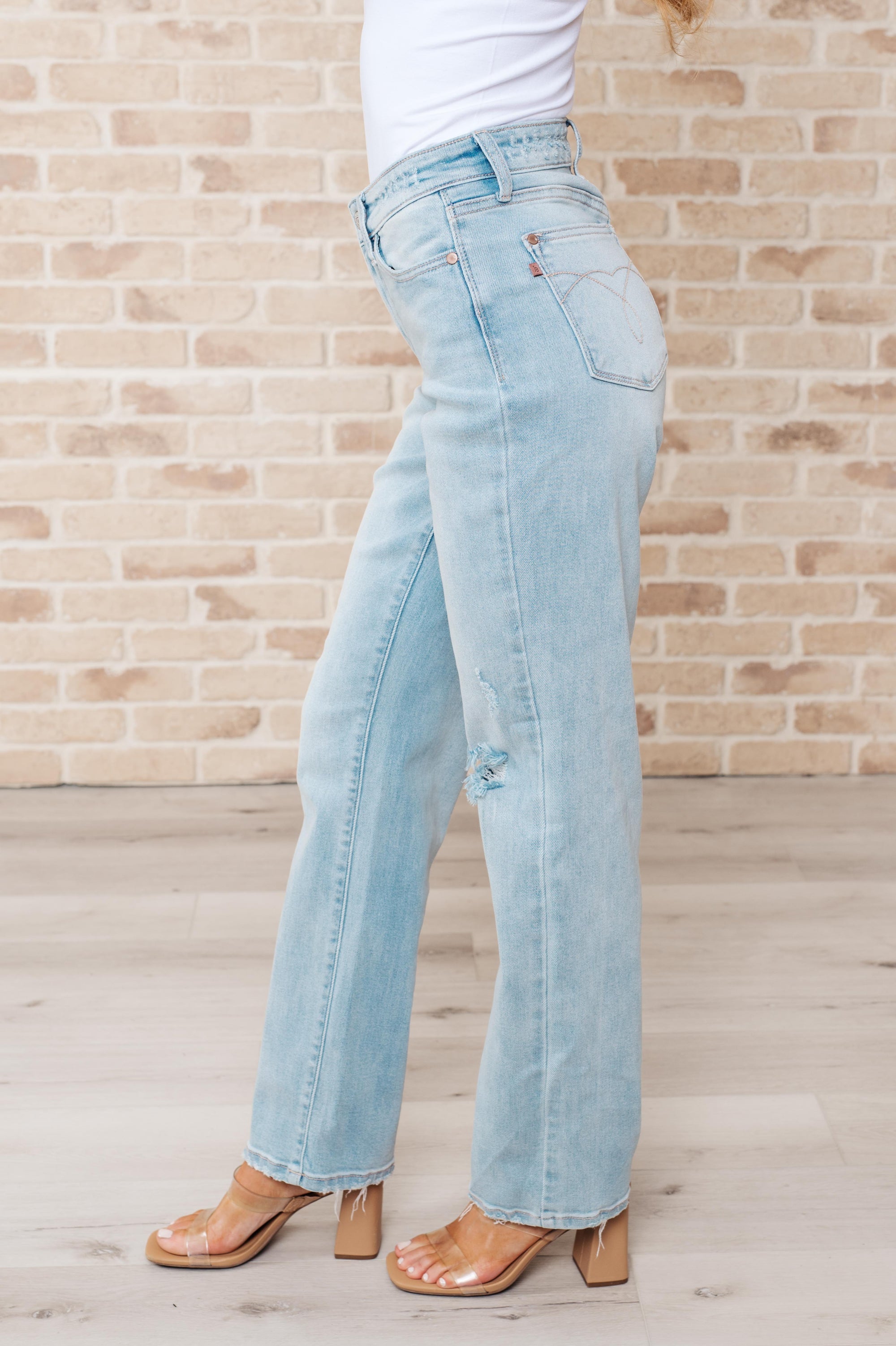 Light blue jeans worn by a person against a brick wall.