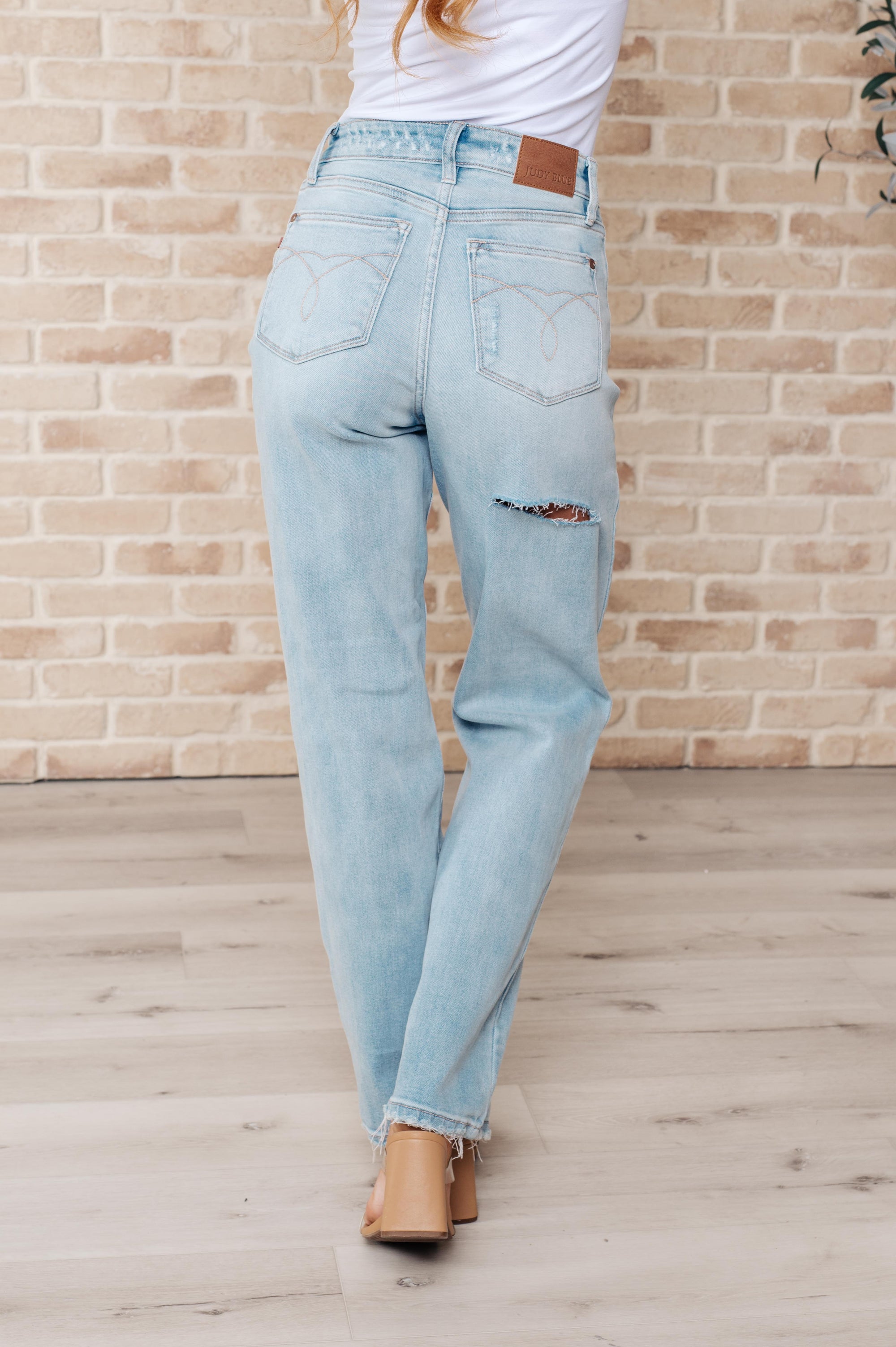 Light blue jeans worn by a person against a brick wall.