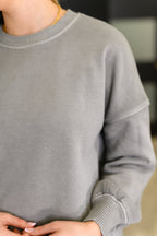 Gray sweater worn by a person with a blurred background