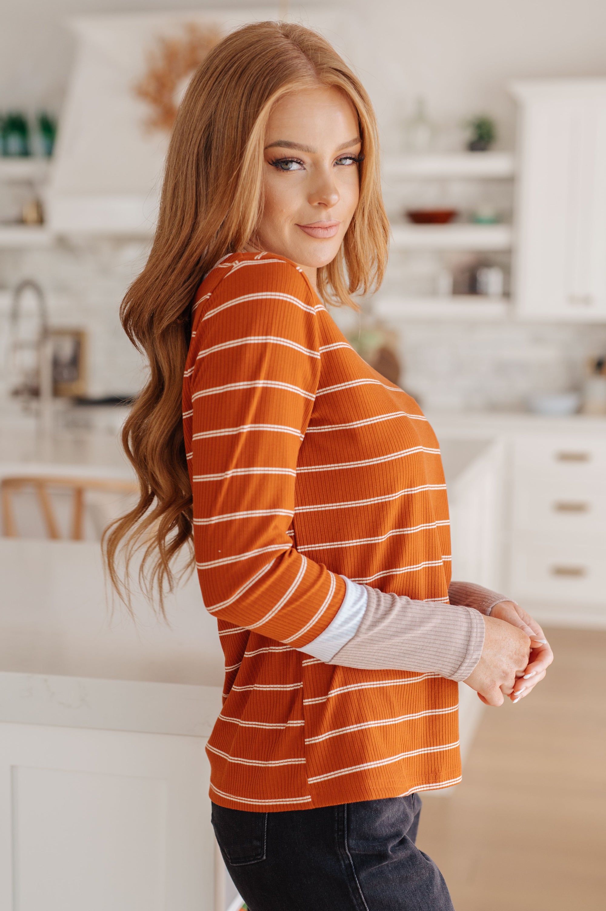 Woman wearing an orange striped shirt in a kitchen