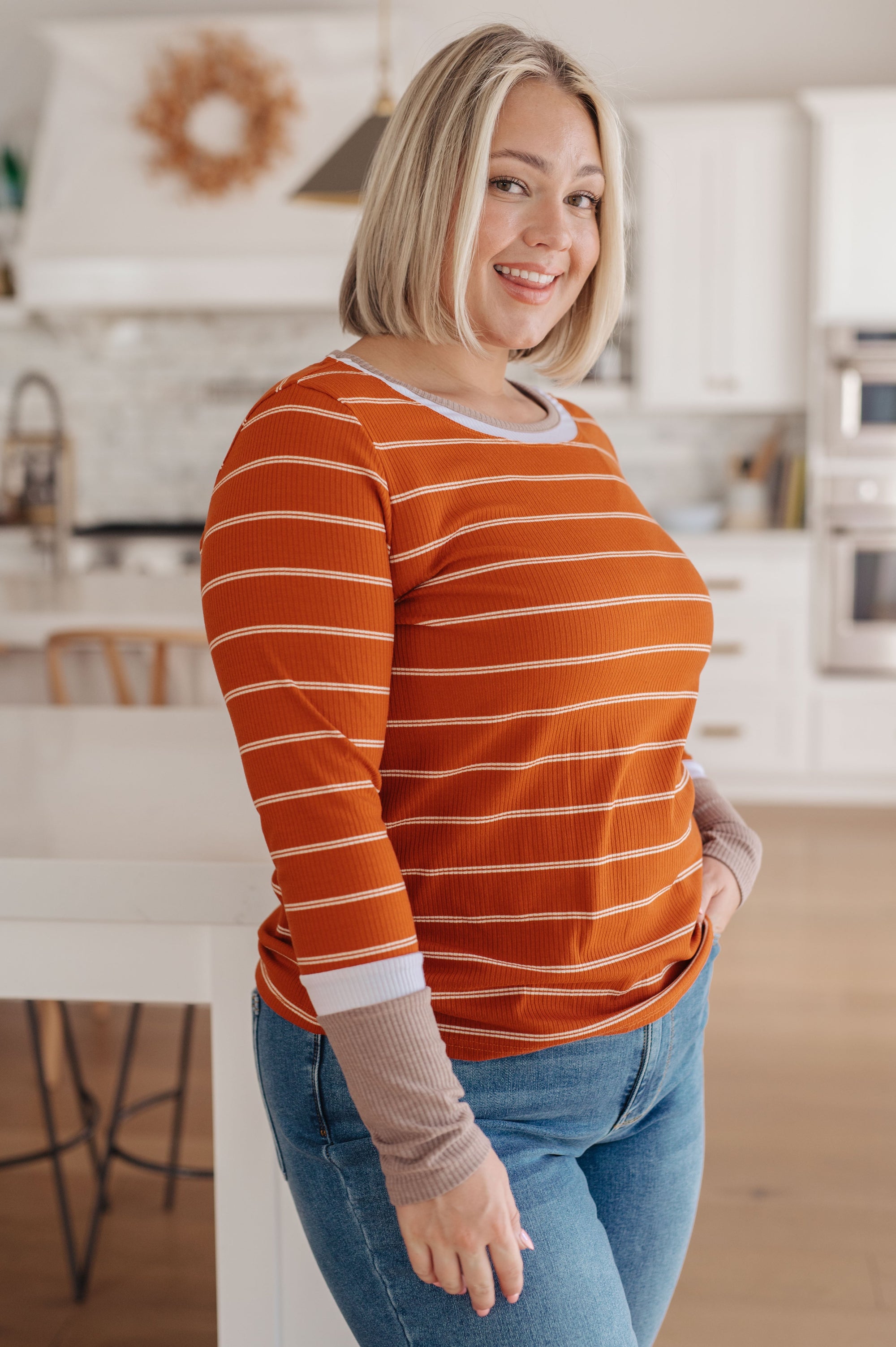 Woman wearing an orange and white striped shirt in a kitchen