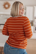 Woman wearing an orange and white striped shirt in a kitchen setting