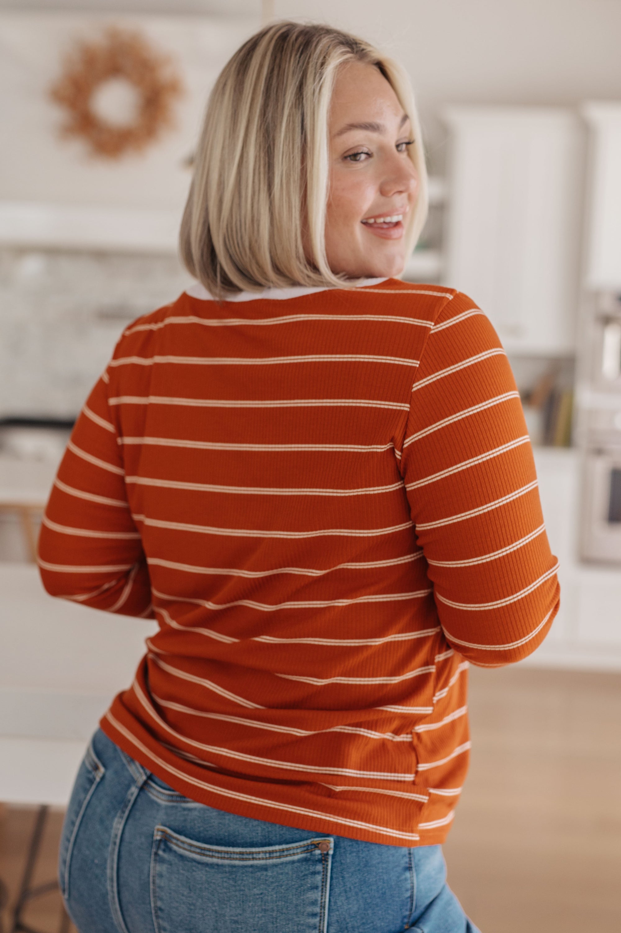 Woman wearing an orange and white striped shirt in a kitchen setting