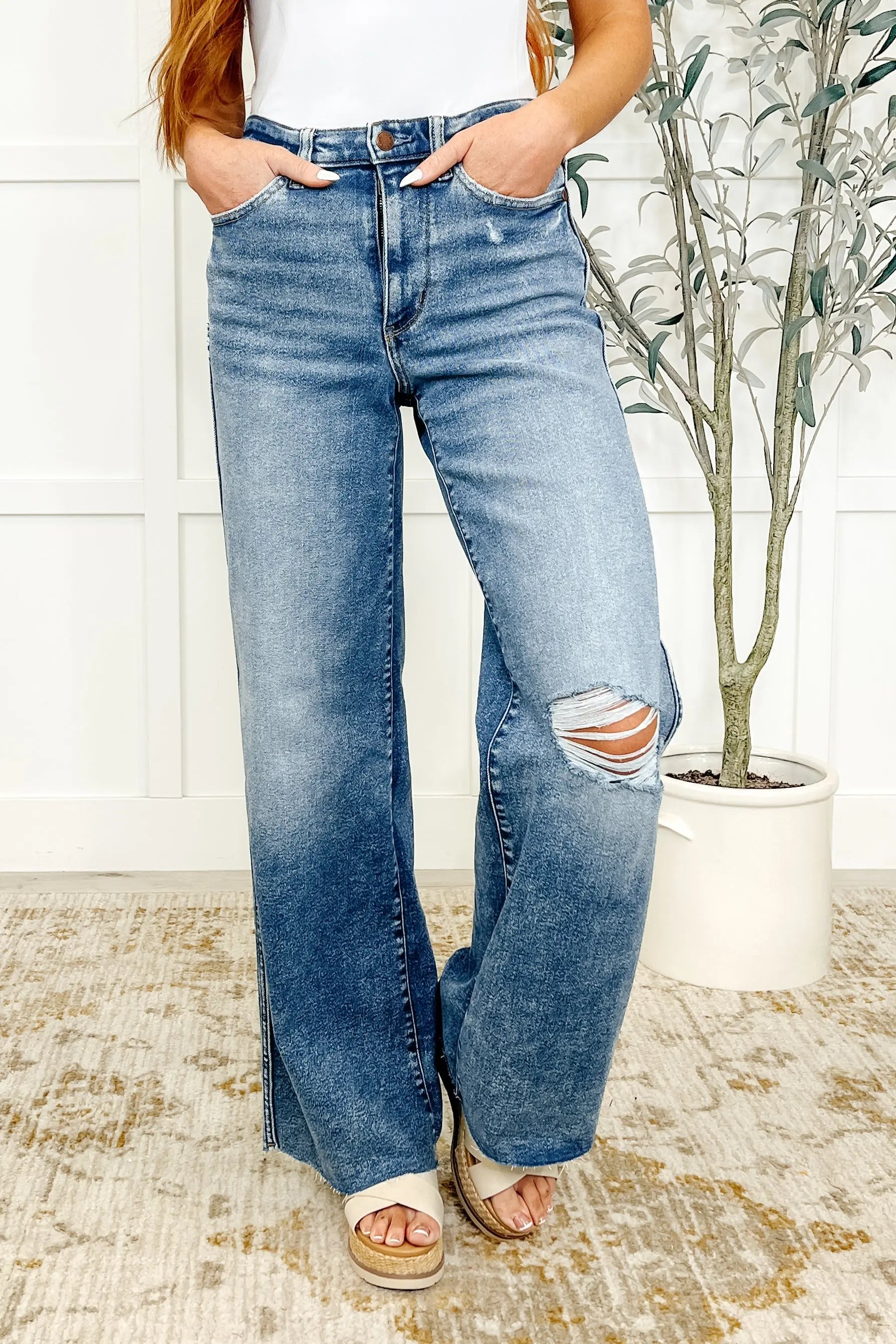 Person wearing blue jeans with a slight distressed look, standing indoors.