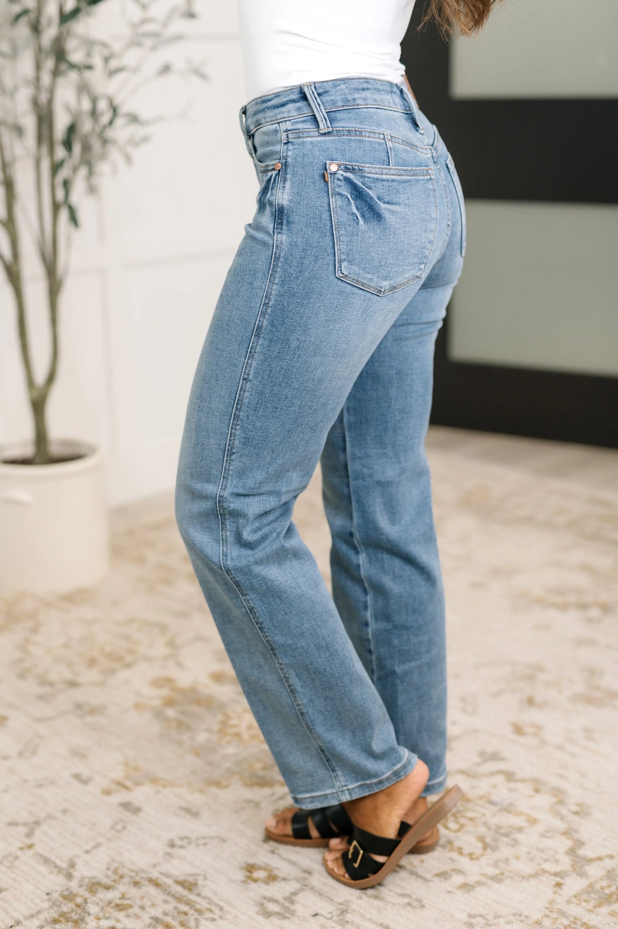Person wearing light blue jeans standing on a textured floor with a blurred background